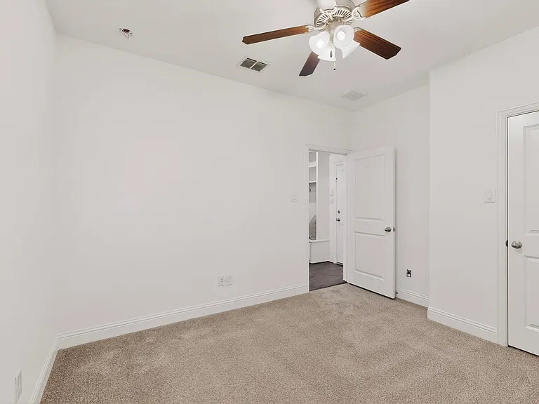 A bright bedroom featuring a ceiling fan and a walk-in closet