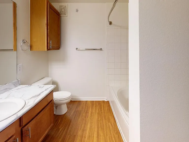 Apartment bathroom with wood-style flooring and marble-style countertops (shown here). Quartz-style countertops are available in select homes.