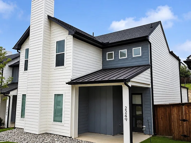 Modern exterior featuring white and gray horizontal siding, a black metal roof, and a covered entry