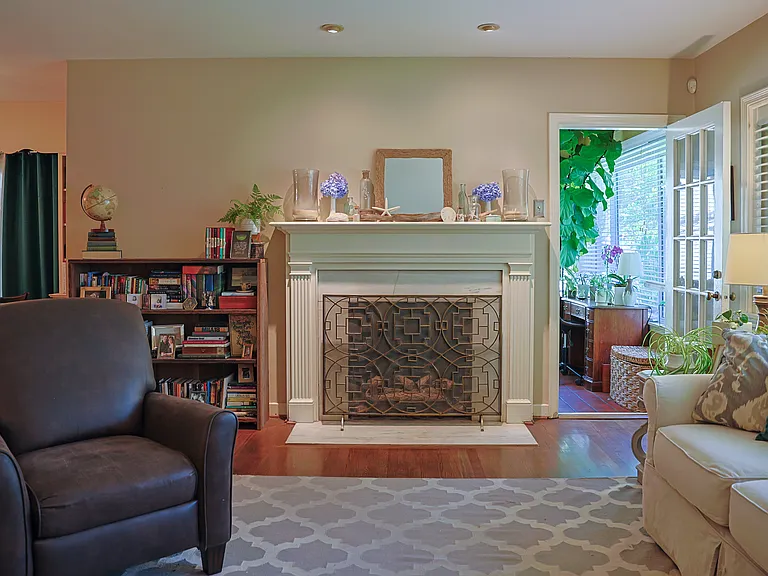 A marble fireplace with working gas logs keeps things extra cozy in the winter. An original glass paned door leads to the sunroom (right) . The glass doors in the dining room (left) open onto the screened porch.