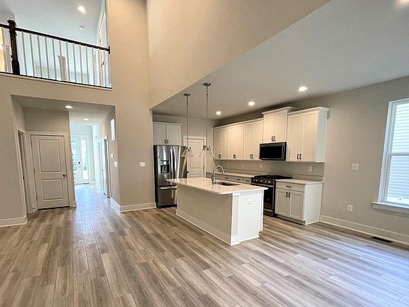 2-story, open kitchen, family room and dining area with medium toned wood floors and large windows.