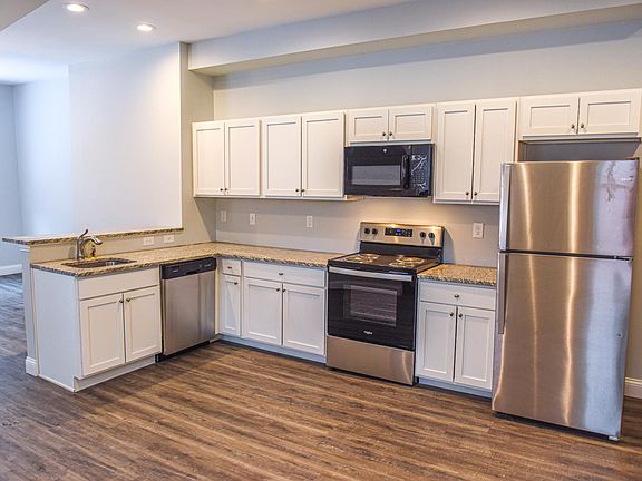 kitchen/dining space with gray vinyl flooring, stainless steel appliances, tons of cabinet space, pantry, granite countertops, and bar height countertops for extra seating