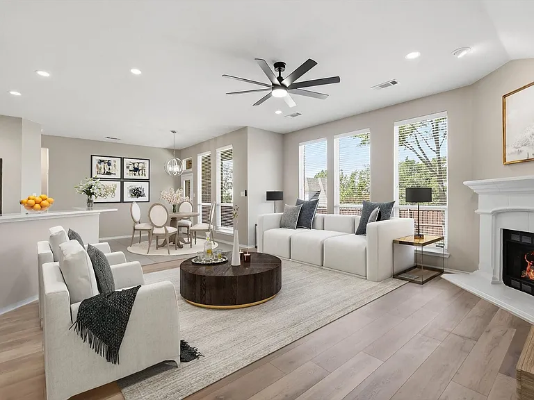 Expansive living area featuring light wood-finish flooring and a corner fireplace with a white mantel