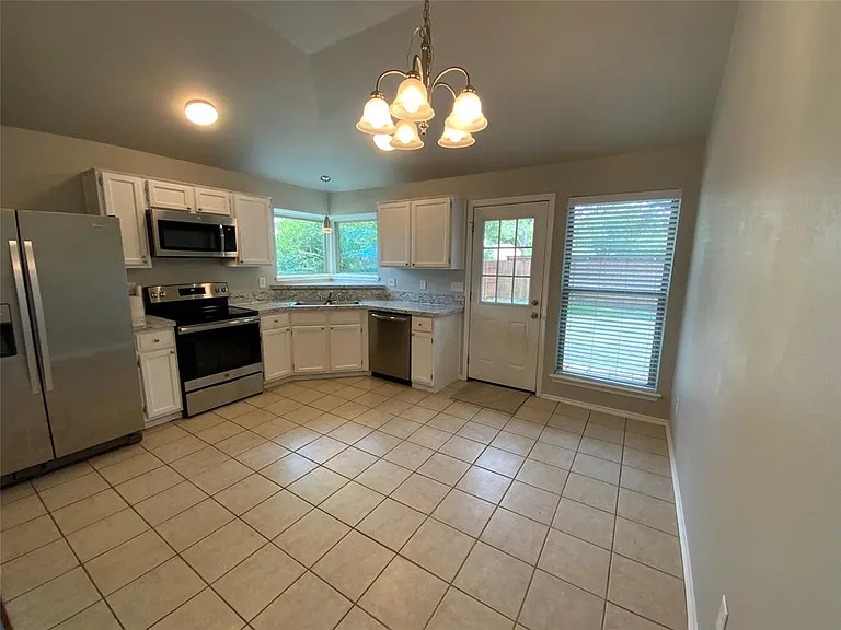 Kitchen featuring white cabinetry, stainless steel appliances, speckled countertops, and tile flooring