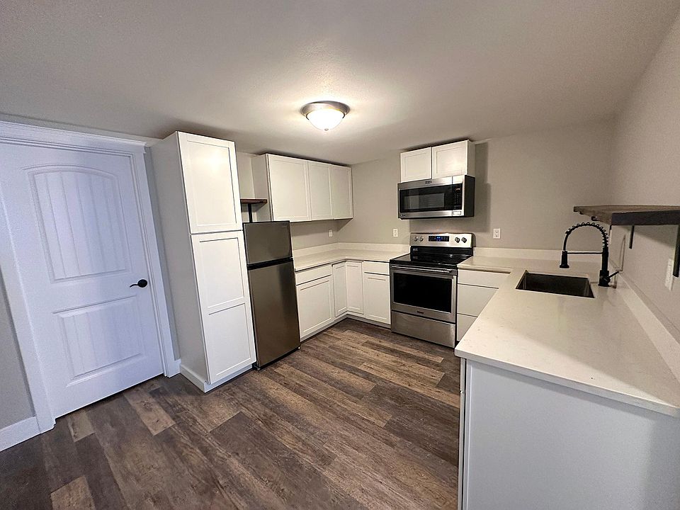 Kitchen features new cabinets, quartz counters, and stainless appliances. Door leads to storage area.