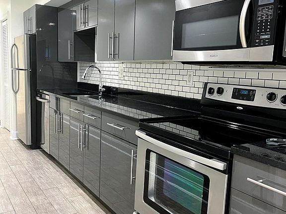 modern galley kitchen with stainless steal appliances and stone counter top