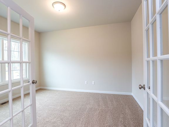 Bright, empty room in one of the new homes in Richmond VA with beige carpet, cream walls, French doo
