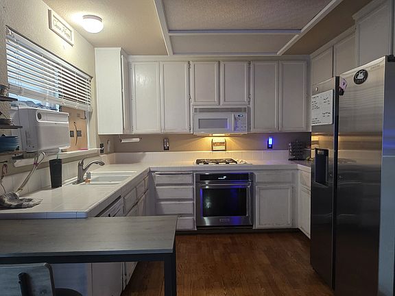 Kitchen area small breakfast nook with bar stools. Opens to a family room that has a gas fireplace and 60 60-inch flat screen TV surrounded by leather couches.