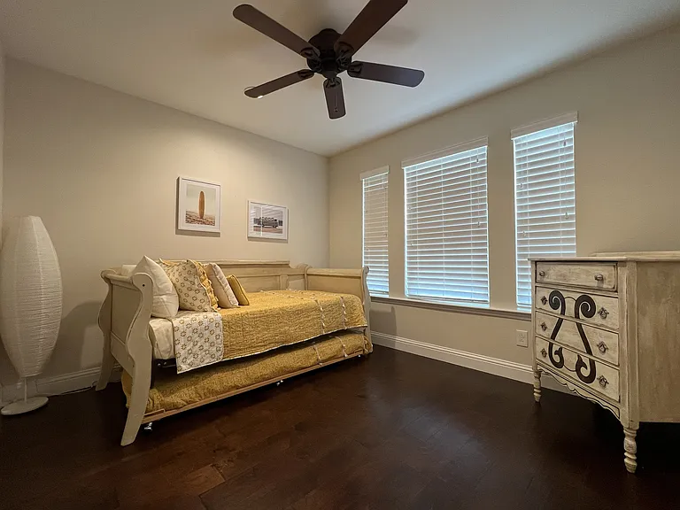 Bright third bedroom with trundle bed, hardwood flooring, and oversized windows.