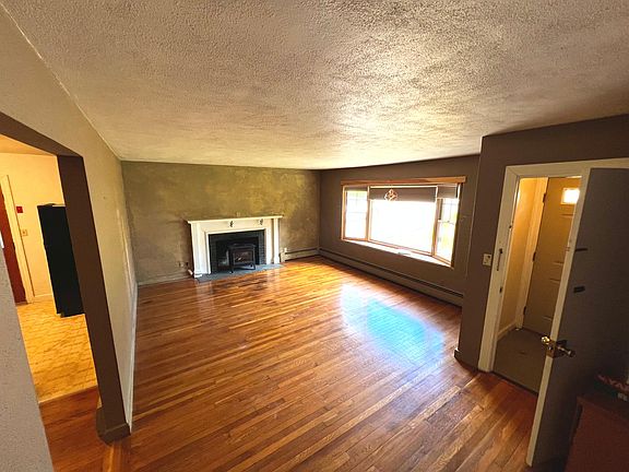 Big spacious living room with a fake fireplace and big window with a view of the front yard