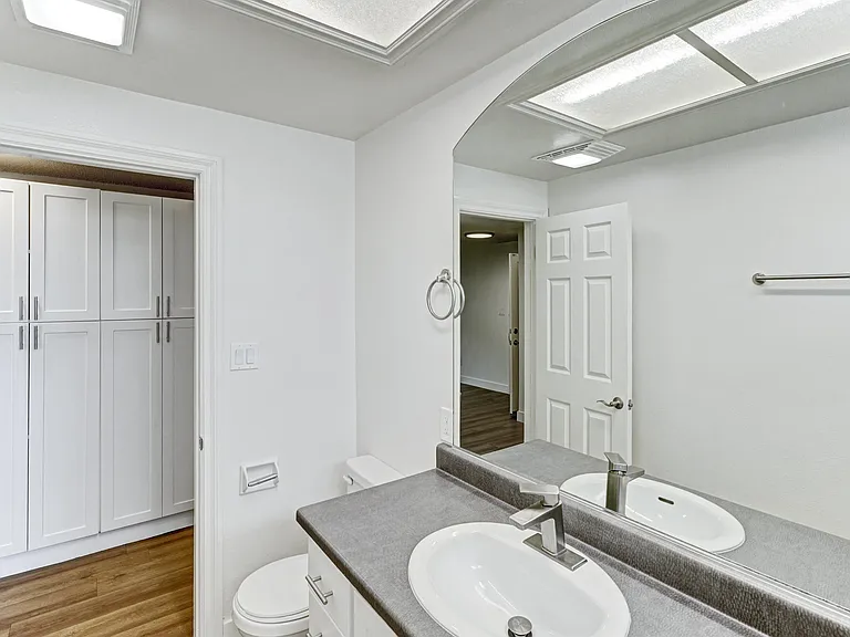 A bathroom with a toilet, sink, and mirror.