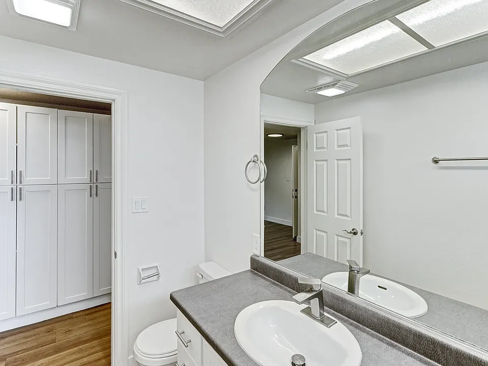 A bathroom with a toilet, sink, and mirror.