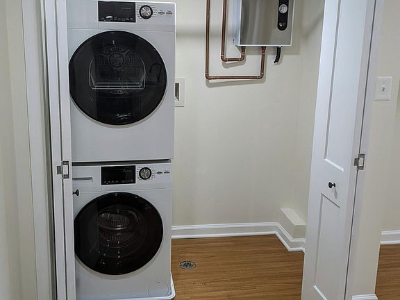 Front closet includes brand-new stacked washer and dryer, hanging rod for coats, and additional storage space