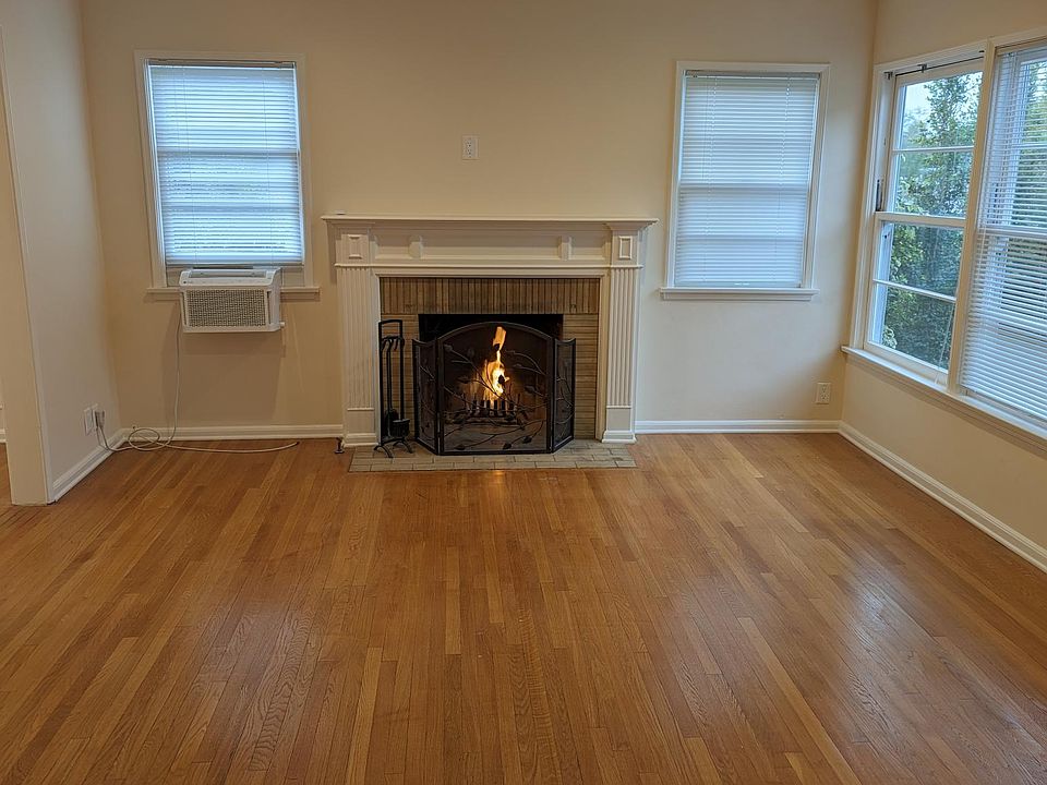 Living room with recessed lighting, hardwood floors, wood burning fireplace, app-controlled GE Profile saddle air conditioning unit.