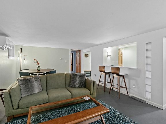 Living room, dining room, bar area, and door to bedroom.