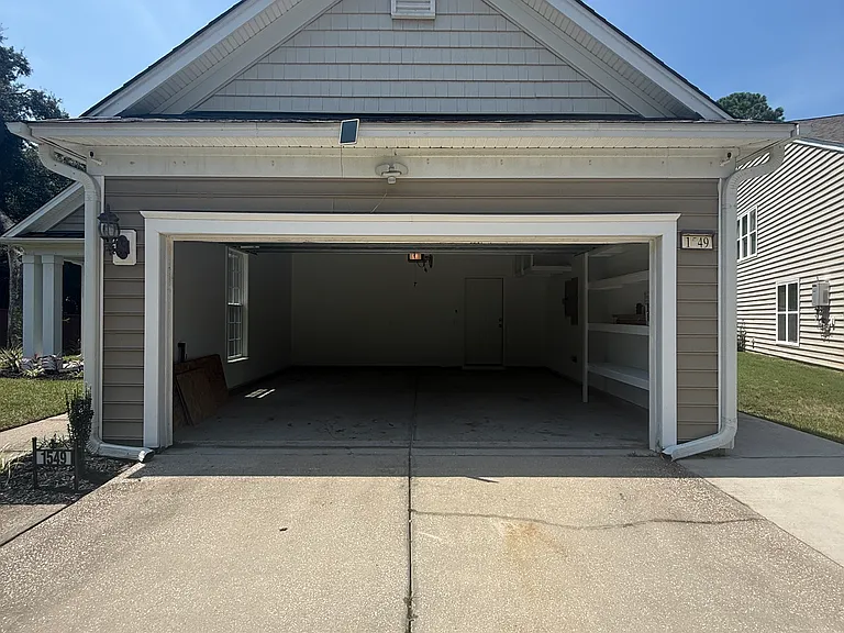 Spacious two-car garage featuring built-in storage shelving and a bright window for natural light."