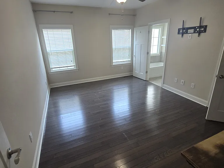 This primary suite serves as a true private retreat, offering an expansive layout that easily accommodates a king-sized bed and additional seating. Features include high ceilings and a dedicated en-suite bathroom with modern fixtures.