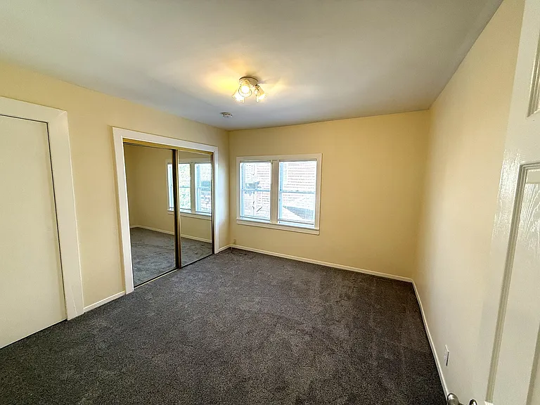 Center bedroom with mirrored closet doors and east-facing windows