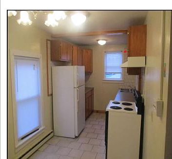 **The kitchen has newly installed curtains and is quite spacious, allowing for plenty of natural light. It is also equipped with base and wall-mounted cabinets that provide a lot of storage space.