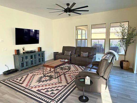 Living room with mounted TV, sound system, record player, and reclining sofas