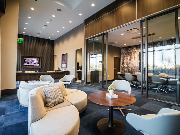 Resident lounge with conference room, soft carpeting, lounge seating, work spaces and a TV