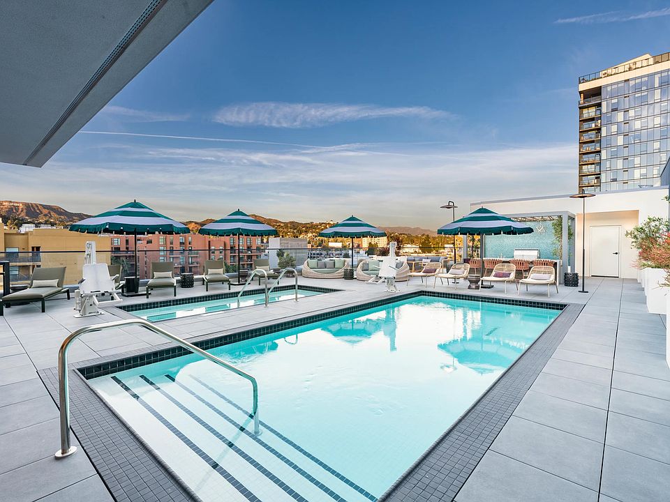 The rooftop pool, designed in a resort-style, features comfortable daybeds and shaded areas for relaxation.