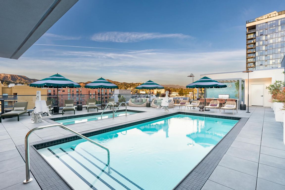 The rooftop pool, designed in a resort-style, features comfortable daybeds and shaded areas for relaxation.