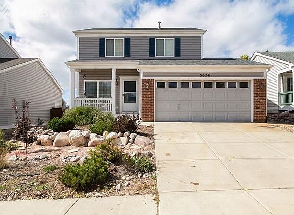 Xeriscape front yard, covered front porch, and cement path around the side of the home to access the back gate and custom shed.