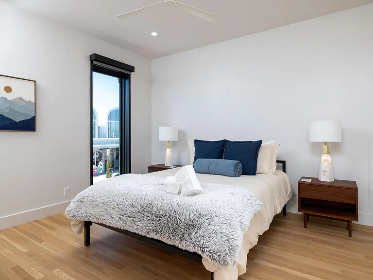 Primary bedroom showcases new artwork, a queen bed, floor-to-ceiling windows for natural light, and an attached bathroom for added convenience.