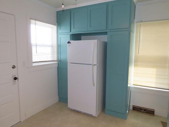 fridge surrounded with cabinets, 2 windows, and back door.
