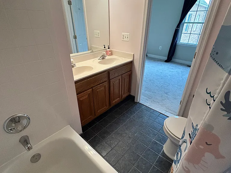 Back facing bedroom attached full bath with twin vanities, bathtub and shower.
