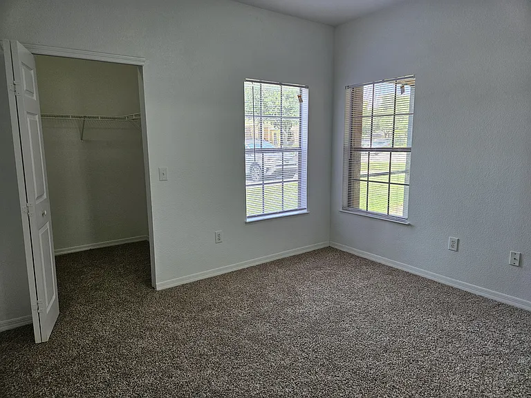 Cozy and spacious bedroom with plenty of natural light and ample walk-in closet space for comfortable living.