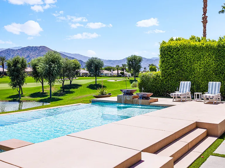 This oasis features a pool and spa with cascading waterfalls, poolside loungers, multiple fire pits including an electric fireplace, a four-hole putting green, a covered patio for outdoor dining, and more!