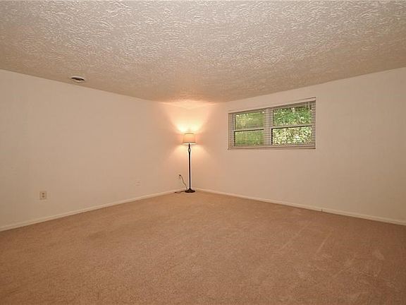 The living room is very spacious with neutral colors. Natural light enters the room from the window seen in the photos. The blin