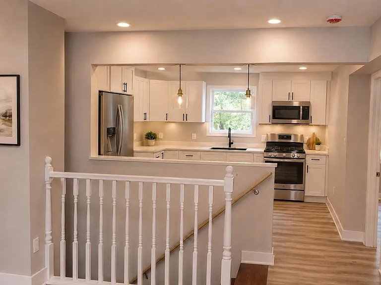 Open kitchen with shaker cabinetry, ample counters, and stainless appliances, plus a window over the sink for natural light.