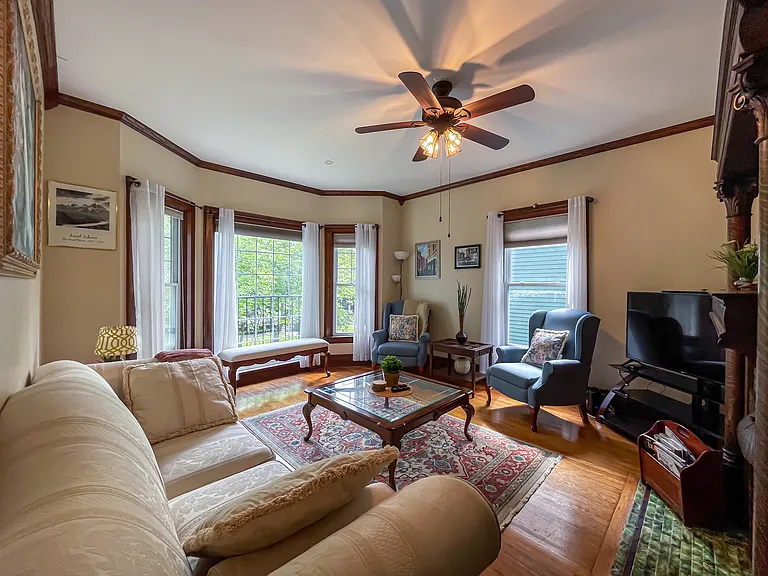[Living Room] Spacious room with large windows, provides a beautiful view of a tree-lined street.