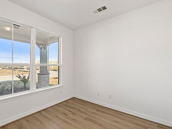 The home office features French doors, beautiful floors, large windows that give a fresh feel, this