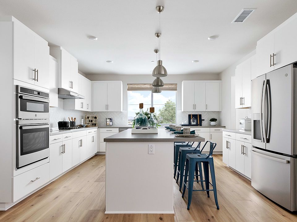 A modern, bright, and spacious kitchen with white cabinets, stainless steel appliances, and a centra