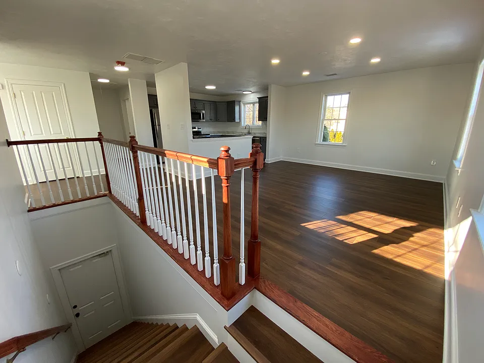 Staircase leading up to unit and open concept main living area with recessed lighting.