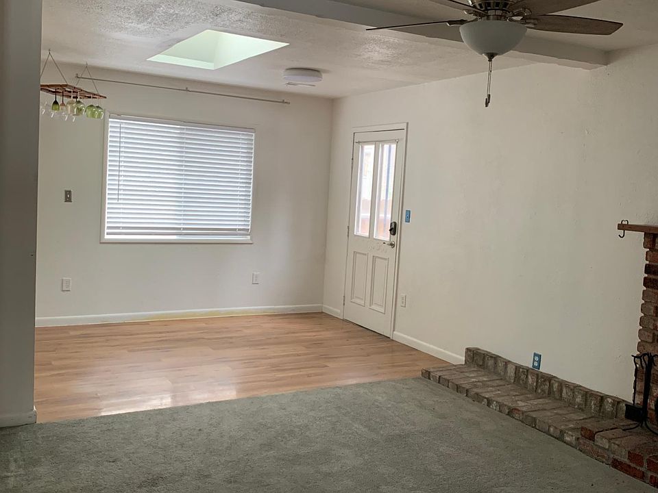 Dining room area with side door to deck, wood-style white shades facing deck and forest