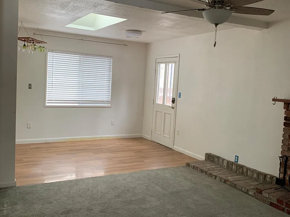Dining room area with side door to deck, wood-style white shades facing deck and forest