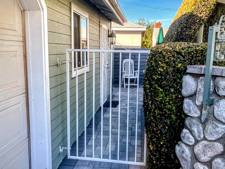 Gate between front house back yard and studio. Privacy hedges