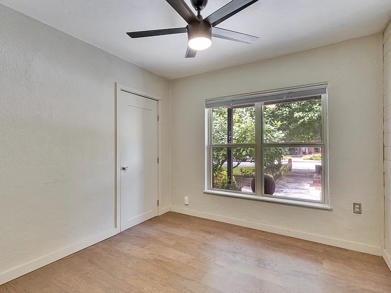 Bedroom #1 has a view looking out to the front yard beneath the shade of the covered front porch