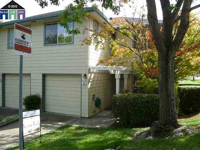 Property front patio courtyard & arbor, entrance & driveway. End unit with the largest grass & landscaped open area in development.