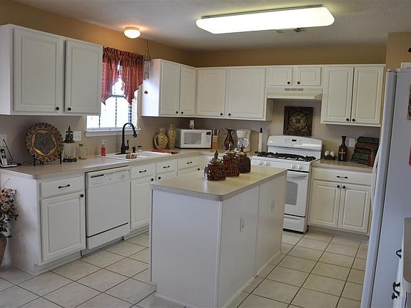 Open kitchen with a lot of cabinet space, tile floors and center island.