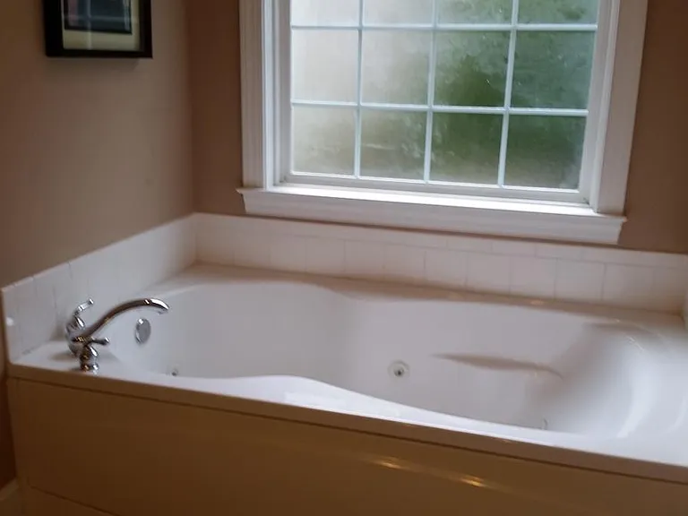 Jetted tub in large first-floor master bathroom, also has two sinks, toilet, stand-in shower, and large walk-in closet