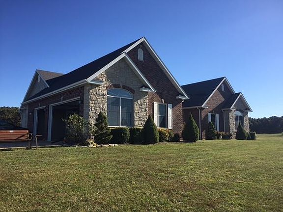 Angled front view showcasing the full brick and stone exterior and attached garage.