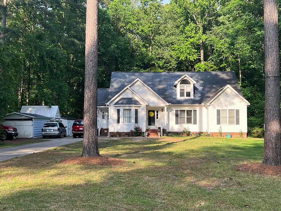 House is set back off of the street with a long driveway and surrounded by woods
