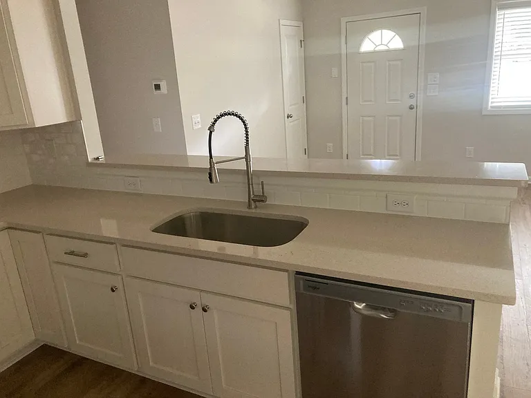 Kitchen with quartz countertops. Showing sink and dishwasher.