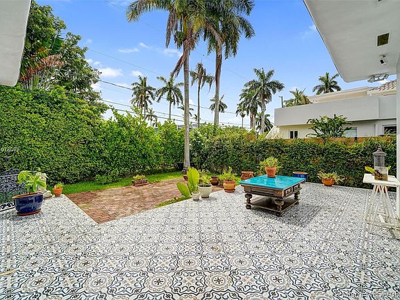 Exterior  full wraparound elevated deck with eclectic Spanish tile design. Steps down onto stone paver patio. French doors from living room and also French doors from the primary bedroom.